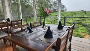 a wooden table with a vase of flowers on it at Cottage Mountain Misty-Nuwaraeliya in Nuwara Eliya
