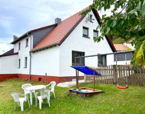 a house with a table and chairs and a playground at Ferienwohnung Marlene 80 Qm in Ebersburg
