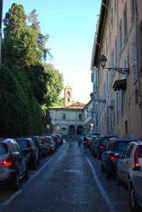 羅馬的住宿－Giulio Caesar，一条有停车车辆的街道和一座有钟楼建筑