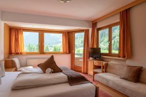 a bedroom with two beds and a couch and windows at Alpine B&B including summercard in Plangeross