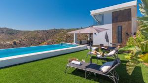 a villa with a swimming pool with chairs and an umbrella at Villa Alborada Torrox by Ruralidays in Torrox