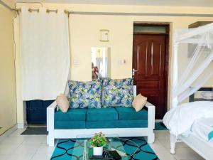 a living room with a blue couch and a bed at Euphglory studio in Kakamega