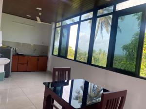 a kitchen with a table and chairs and windows at DOWN TOWN HOLIDAYS Kovalam in Kovalam