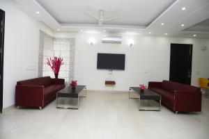 a living room with two red couches and a flat screen tv at Hotel O Vagmi Residency - Grand in Gurgaon +16 photos