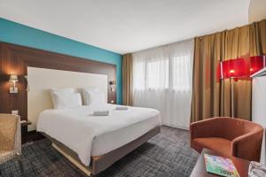Una habitación de hotel con una cama grande y una silla. en Mercure Paris Porte d'Orleans, en Montrouge