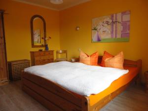 テンプリーンにあるFerienhaus Krügerのベッドルーム1室(白いシーツとオレンジの枕が備わるベッド1台付)