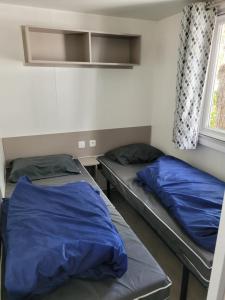 2 camas en una habitación con sábanas azules y ventana en De l'Anse à la Coubre, en Les Mathes