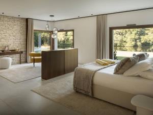 a bedroom with a large bed and a living room at Villa Luxe au Cœur des Landes - Architecture d'Exception - FR-1-791-43 in Magescq