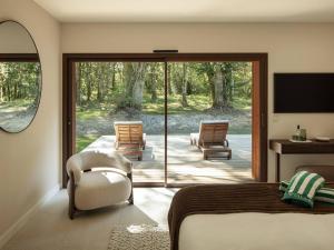 a bedroom with a bed and a patio with chairs at Villa Luxe au Cœur des Landes - Architecture d'Exception - FR-1-791-43 in Magescq