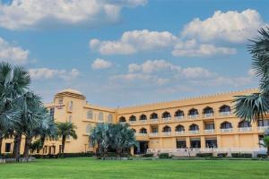 a large building with palm trees in front of it at Haut Monde Rajputana Palace in Behror