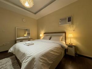 a bedroom with a large white bed and a mirror at شقق فندقية هادئة بحي السلامة in Jeddah