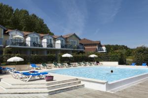 a swimming pool with chairs and umbrellas next to a hotel at Les pieds dans l'eau in Marciac