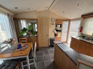 eine kleine Küche mit einem Tisch und einer Arbeitsplatte in der Unterkunft Meadow Lakes 82 - Golden Palm Resort - Meadow Lakes Caravan Hire in Chapel Saint Leonards