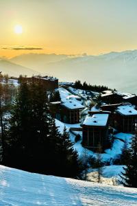 a village in the snow with the sun in the background at Appartement de luxe les Arcs 4 chambres skis aux pieds in Arc 1800