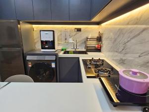 a kitchen with a sink and a stove with a pot at The Quartz Residence - Melaka in Melaka