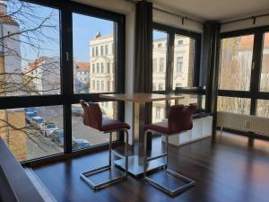 a table and two chairs in a room with windows at Modernes Apartment Stadtfeld Ost Panoramafenster in Magdeburg +8 photos