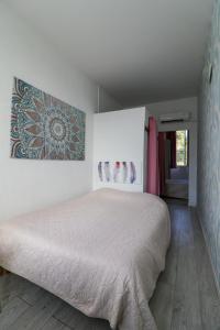 a bedroom with a white bed with a picture on the wall at Le Telo in Saint-Mandrier-sur-Mer