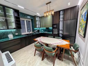 a kitchen with a wooden table and green chairs at Green Garden Villa & Pool in Tirana