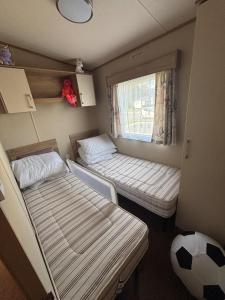 ein kleines Zimmer mit zwei Betten und einem Fenster in der Unterkunft The Retreat 36 - Golden Palm Resort - Meadow Lakes Caravan Hire in Chapel Saint Leonards