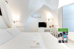 a white bedroom with a white bed and a desk at Masseria Lamagrotte By Raro Villas in Rosa Marina +95 photos