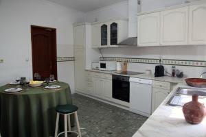 een keuken met witte kasten en een groene tafel. bij Casa do Sossego in Safara