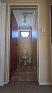 a bathroom with a toilet and a door with a window at Polka Apartment in Ranfurly