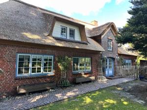 a brick house with a fence in front of it at Stilvolle 2 5 Zimmer Wohnung unter Reet in SPO mit Garten in Sankt Peter-Ording +43 photos