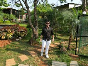 a man standing in the grass in a yard at Lake House in Malavli