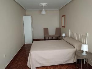 ein Schlafzimmer mit einem weißen Bett und zwei Stühlen in der Unterkunft Vivienda Vacacional Alba Marinas in Pravia