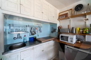 エンプリアブラバにあるAppartement Bord de Mer Karina 1 by Welhomyの白いキャビネットとシンクと電子レンジを備えたキッチン