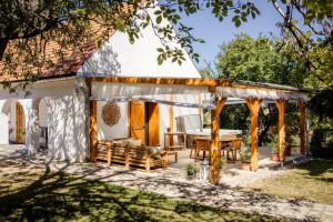 a pavilion with a table and chairs in front of a house at D9 Cottage in Csesznek