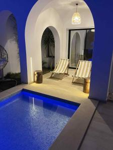 a house with a swimming pool with two chairs next to it at Villa bella blanca in Hammamet +1 photo