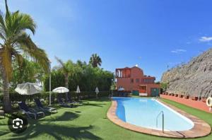 a resort with a swimming pool and chairs and a building at Apartamento en Pasito Blanco PTOM11 in Pasito Blanco