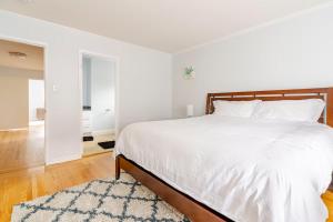 a white bedroom with a large bed and a rug at Malcolm Commons in Oakland