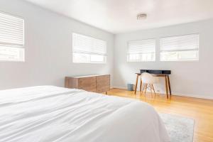 a white bedroom with a bed and a desk at Malcolm Commons in Oakland