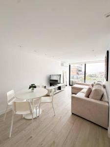 a white living room with a table and a couch at Rincón Albufereta Piscina, Sierra y Mar in Alicante