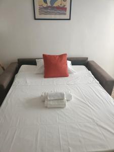 a large white bed with a red pillow and two towels at Trilocale sul mare - SOLEeSALE in Pescara +2 photos