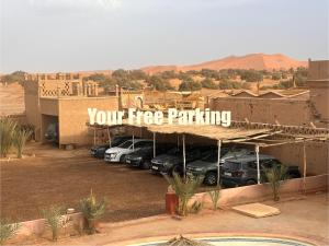 a parking lot with cars parked in front of a building at Merzouga Spirit Luxury Camp in Merzouga