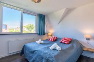a bedroom with a blue bed with red and white pillows at Hoogelandt 126 in De Koog +10 photos