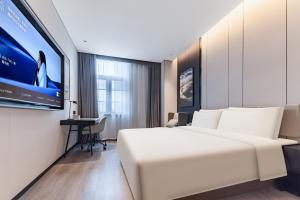 Atour Hotel Shanghai North Bund Dalian Road في شانغهاي: غرفة فندق بسرير ابيض وتلفزيون بشاشة مسطحة