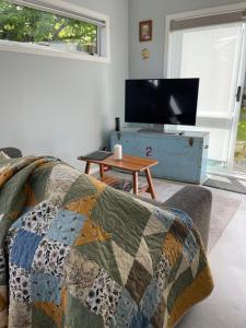 a living room with a couch and a tv and a table at Modern Garden Cottage with Private Outdoor Area - New Lynn in Auckland