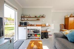 a living room with a white refrigerator and a table at Modern Garden Cottage with Private Outdoor Area - New Lynn in Auckland +15 photos