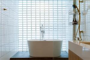 a bathroom with a tub in front of a window at Horizontel in Chiang Rai