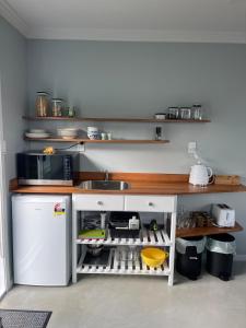 a kitchen with a sink and a white refrigerator at Modern Garden Cottage with Private Outdoor Area - New Lynn in Auckland