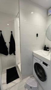 a bathroom with a washing machine and a sink at White Apartment in Liepāja