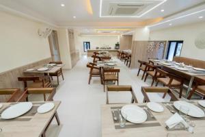 uma sala de jantar com mesas e cadeiras de madeira e tablesearcher em Hotel Pritam, Nagpur em Nagpur