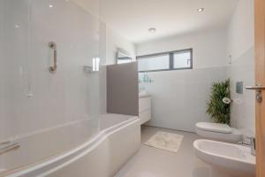 a white bathroom with a tub and a toilet and a sink at Underhill in Corfe Castle +26 photos