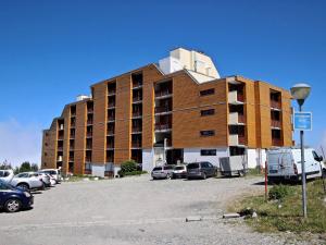 un grand bâtiment avec des voitures garées dans un parking dans l'établissement Coquet studio cabine pour 4 avec balcon et accès direct aux pistes - Chamrousse 1750 - FR-1-340-23, à Chamrousse 13 autres photos