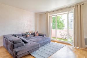 a living room with a couch and a large window at Séjour Cosy - 5 min Aéroport Orly - Parking Privée & Terrasse in Orly