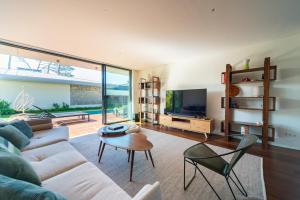 ein Wohnzimmer mit einer Couch, einem Tisch und einem Fernseher in der Unterkunft Cascais Sandwoods Luxury Villa in Cascais